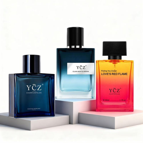 Three YCZ Charmant Lights perfume bottles displayed on white and light gray pedestals against a clean white background. The left bottle is dark blue, the middle bottle is light blue, and the right bottle is orange-red with the text 'Putting You Closer LOVE'S RED FLAME'.